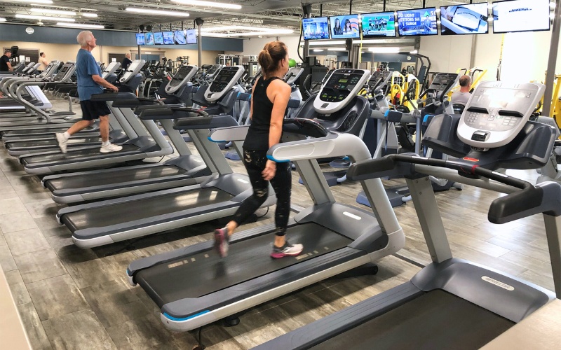 a woman walks on a treadmill in the cardio section of a furlong gym near me