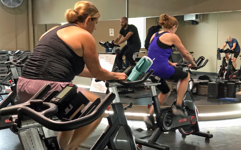 gym members pedal on spinning machines during an intense cycling class at a furlong gym