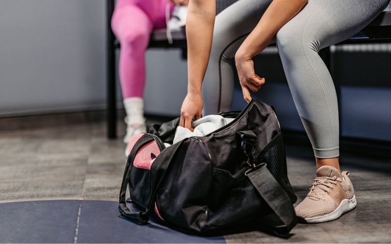 a gym member reaches into their gym bag in a private locker room at a spacious furlong gym