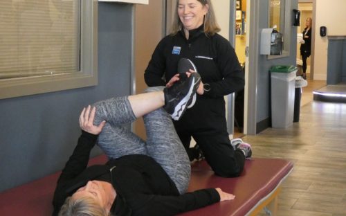 a certified personal trainer helps a gym member stretch her legs during a training session at a doylestown gym