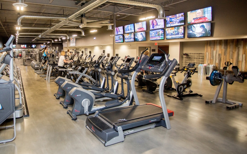 a row of treadmills, elliptical machines, at a modern new hope gym