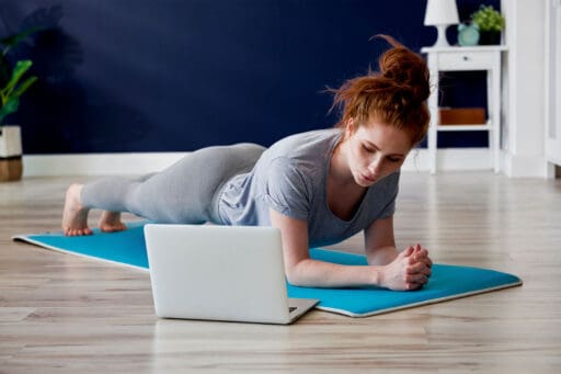 woman on the floor using a computer as she works out