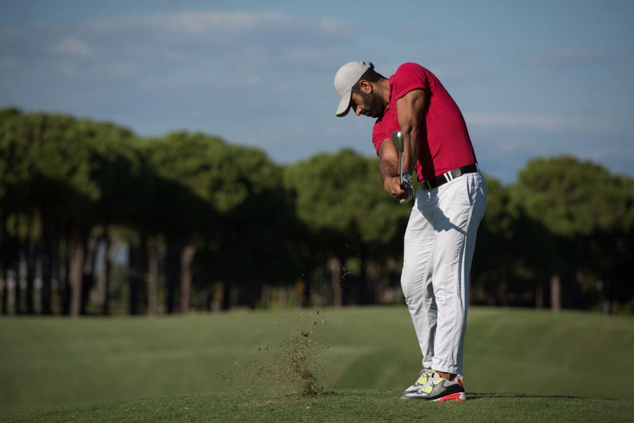 Man swinging a club on a golf green.