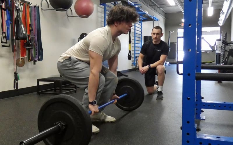 a young man deadlifts free weights at a bucks county gym with a certified personal trainer