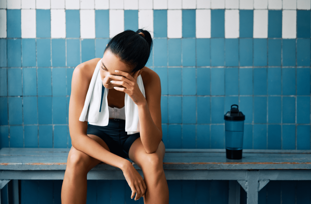 A fit woman sitting on a bench with a posture of frustration