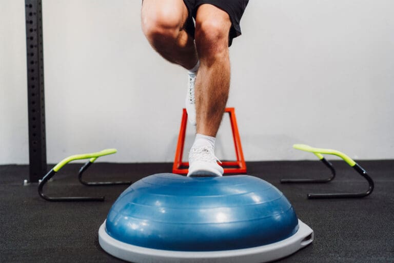 Person standing on one leg on a bosu ball.