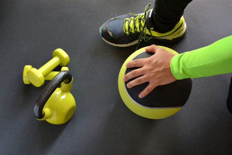 Man holding a medicine ball on the floor.