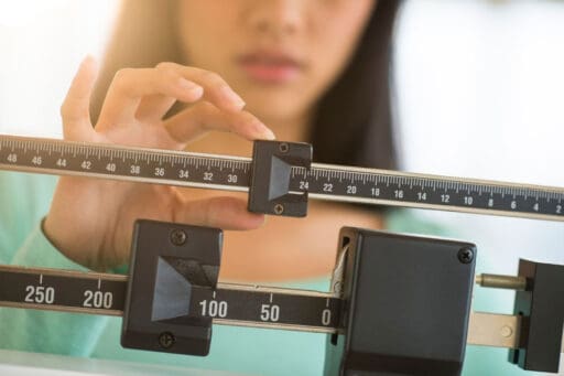 Woman adjusting the weights on a scale.