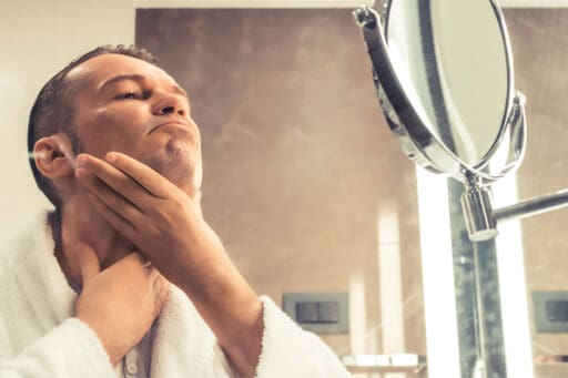 Man examining his face in the mirror.