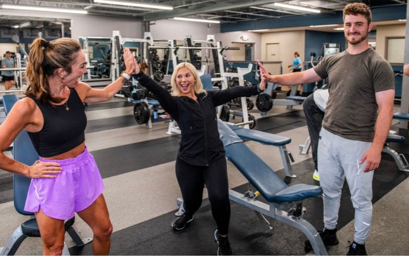 Personal trainer celebrates a successful workout with two members at Cornerstone Health & Fitness