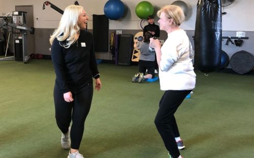 a certified personal trainer helps a gym member with a kettle bell squat workout at a bucks county gym